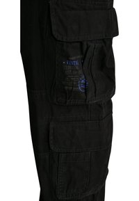 Černé cargo kalhoty vyrobené z odolné látky, s několika kapsami, prošívanými detaily a modrou etiketou s informacemi o značce.