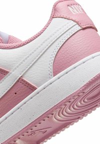 Sneaker rosa e bianca con tomaia in pelle texturizzata, punta arrotondata, design laterale a contrasto e suola in gomma con battistrada decorato.