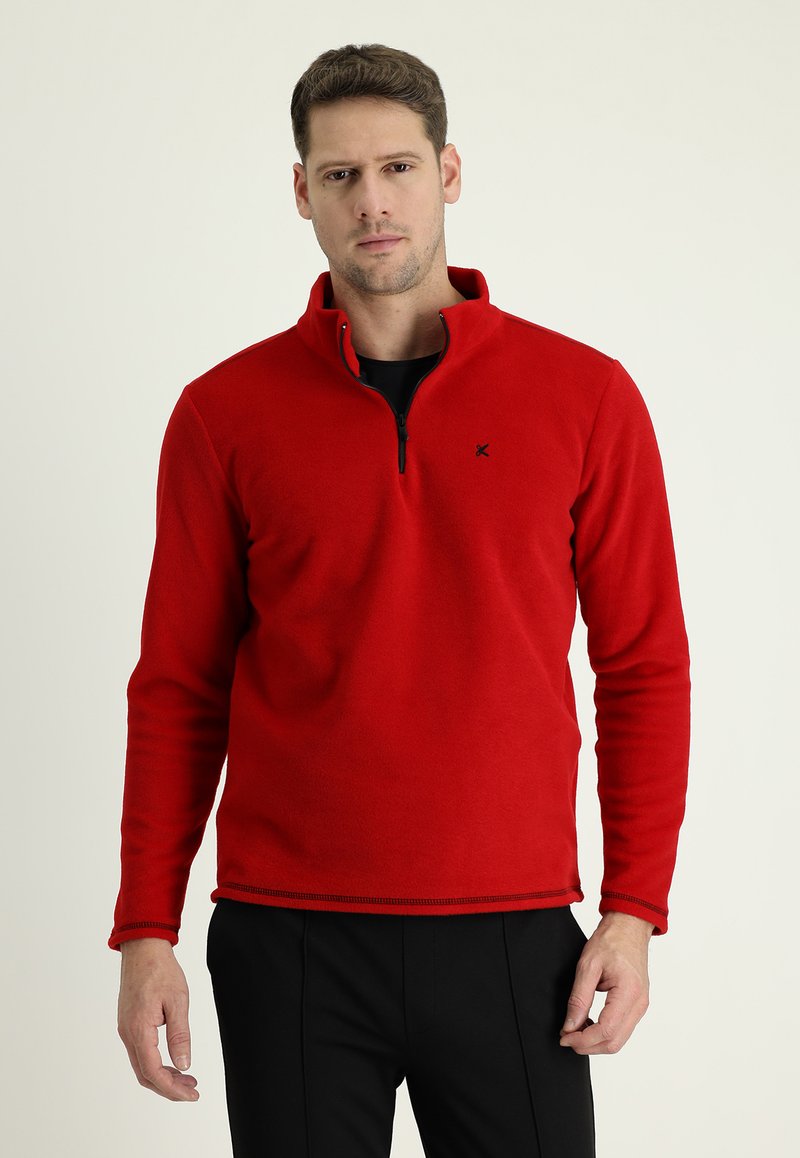 Pullover in pile rosso con colletto a mezza zip, maniche lunghe e un logo discreto sul petto. Texture liscia, vestibilità casual e orlo cucito.
