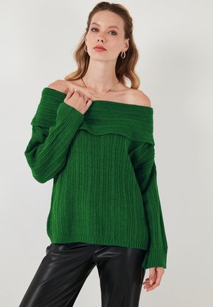 Žalios juostelės off-shoulder megztinis su ilgomis rankovėmis, tekstūruotas mezginys ir banginiu ausku. Suderintas su juodomis odinėmis kelnėmis.