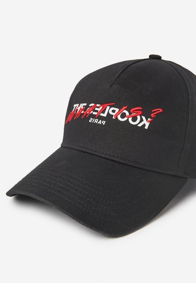 Melnā cepure, kas izgatavota no auduma ar izliekto vizieri. Iezīmēts balts un sarkans izšuvums ar tekstu "Kooples?" un "PARIS." Gluda tekstūra.