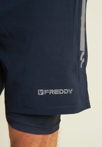 Pantaloni sportivi blu navy realizzati in tessuto liscio, con logo grigio e strisce sui lati, dotati di una fodera interna aderente.