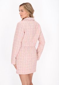 Rosenholzfarbendes Tweedkleid mit einem strukturierten Kragen und langen Ärmeln, das ein strukturiertes Muster und eine taillierte Taille aufweist.