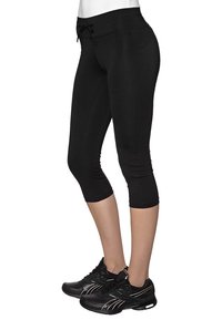 Czarne legginsy capri wykonane z elastycznego materiału, z regulowanym pasem i obcisłym krojem, w zestawieniu z czarnymi butami sportowymi z srebrnymi akcentami.