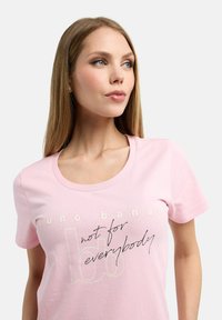 Light pink cotton t-shirt with a round neckline. Features printed text in contrasting colors: "runo banana" and "not for everybody."