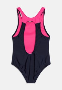 Maillot de bain une-pièce marine avec des accents roses. Présente un design à dos nageur, un détail découpé à l'arrière et un tissu texturé sur l'ensemble.