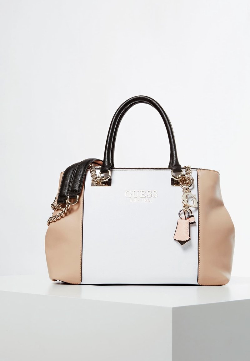 Sac à main structuré blanc et beige avec poignées noires, quincaillerie en argent et un charme ; présente une finition texturée et un détail de logo.