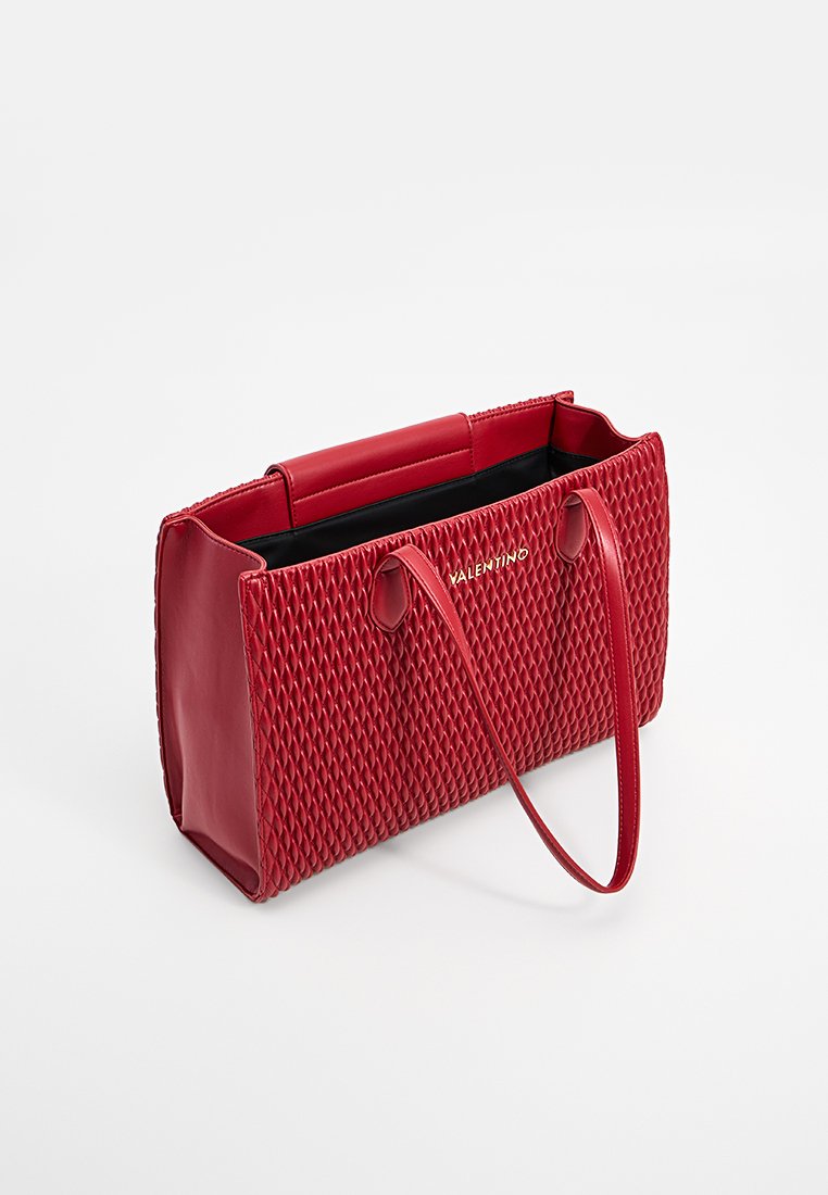 Sac à main en cuir rouge avec une texture en relief diamanté, deux poignées et un intérieur spacieux noir. Présente le logo de la marque sur le devant.