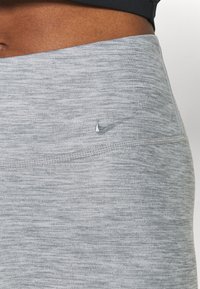 Jasnoszare legginsy sportowe wykonane z teksturowanej tkaniny, z małym logo nad pasem i gładkim, dopasowanym krojem.