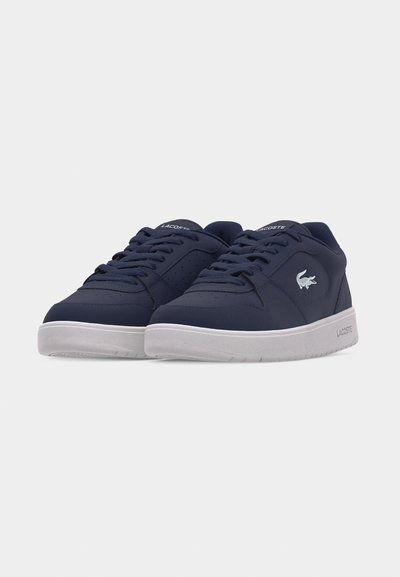 Двойка тъмносини маратонки Lacoste с бели подметки, връзки и лого отстрани, подредени странично една до друга на обикновен бял фон.
