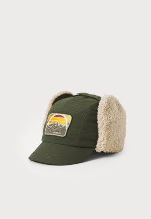 Green hat with a soft cream fur-lined ear flaps, featuring a multicolored patch with mountains and a sun. Durable fabric, curved brim design.