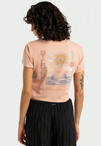 Pink cropped t-shirt featuring a graphic design with sun, eye, and waves. Soft cotton material with short sleeves and a relaxed fit.