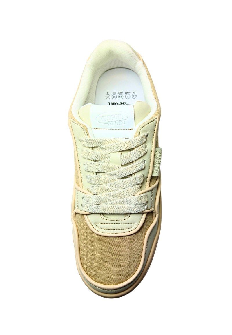 Beige sneaker with a textured fabric upper and smooth synthetic accents. Features a padded tongue and thick laces, minimal logo detailing.
