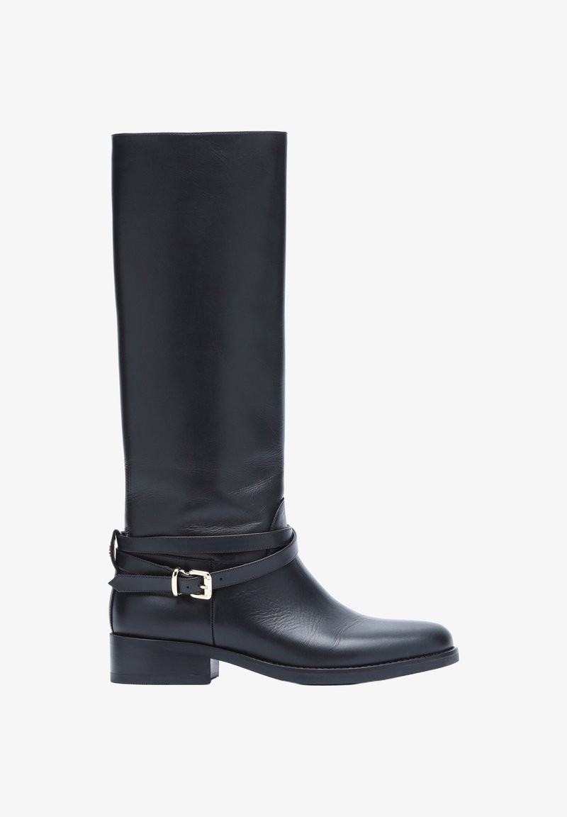 Botte haute en cuir noir avec talon bas et sangle décorative avec boucle argentée autour de la cheville, vue latérale sur fond blanc.