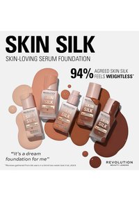 Quattro bottiglie di vetro di fondotinta "Skin Silk" in varie tonalità della pelle, esposte con gocce di fondotinta liquido. Toni rosa chiaro e marroni predominano.