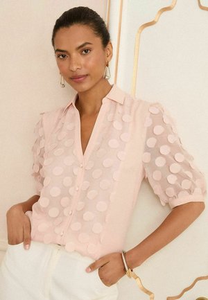 Hellsrosafarbenes Bluse mit Knopfleiste und strukturierten, kreisförmigen Puffdetails an den Ärmeln. Glatter Stoff und lockere Passform.