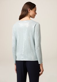 Helles blaues Sweatshirt aus strukturiertem Stoff, verziert mit schimmernden Pailletten. Lange Ärmel mit geradem Saum und Rundhalsausschnitt.
