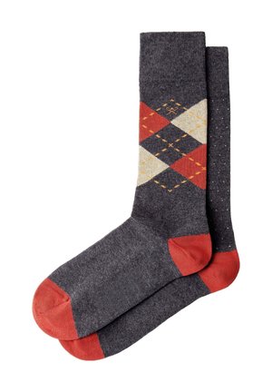 Calcetines gris oscuro con dedos y talones rojos; un calcetín presenta un patrón argyle en rojo, crema y naranja, el otro tiene pequeños puntos blancos.