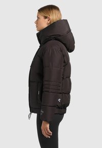 Doudoune noire avec col montant et grande capuche. Comprend des sections matelassées et des poignets élastiques, fabriquée en matériau lisse et léger.