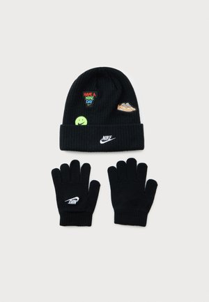 Ensemble d'hiver Nike noir avec bonnet orné de patches colorés et gants avec le logo Nike blanc sur un fond clair.