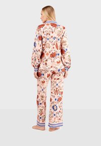 Floral pajama set featuring a soft pink base, multicolored floral patterns, long sleeves with blue cuffs, and decorative trim on pants.