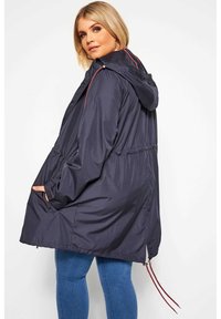 Tummansininen tuulenpitävä takki hupulla, vyötäröstä kireä, sivutaskut ja punaista korostavaa nauhaa helman kohdalla. Sujuva, kevyt materiaali.