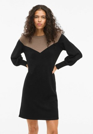 Robe tricotée noire avec un motif en chevrons marron sur la partie supérieure, manches longues, col rond et coupe décontractée. Texture douce.