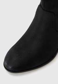 Schwarze Wildledersneaker mit runder Zehenpartie und minimalen Nähten entlang der Naht. Die Sohle ist langlebig und flach.