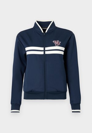 Μπλε σκούρο τζάκετ με φερμουάρ, με λευκές διπλές ρίγες στο στήθος και τις μανσέτες των μανικιών, και ένα μικρό κεντητό λογότυπο στο αριστερό μέρος του στήθους.