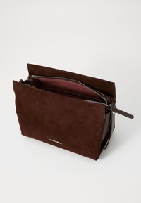Pouch in suede marrone con chiusura a zip, dotato di un interno bordeaux a contrasto e dettaglio del logo sulla parte anteriore. Forma rettangolare.