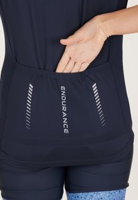 T-shirt de sport marine avec une poche au dos, comportant des accents réfléchissants et un tissu texturé. Comprend un logo avec le mot "ENDURANCE".