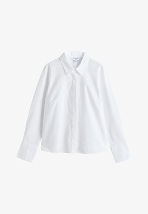 Chemise blanche à manches longues boutonnée, avec col pointu et larges poignets, présentée sur un fond blanc uni.