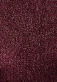 Primo piano di un tessuto di maglia maroon testurizzato, con una superficie morbida e pelosa e modelli intrecciati visibili.