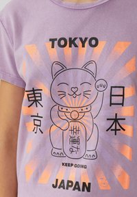 Lila T-shirt met een afbeelding van een maneki-neko (gelukskat) omringd door de teksten "TOKYO", "日本", en "HOU DOOR" in zwart en oranje.