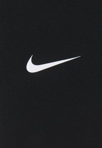 Czarna tkanina Nike z wyraźnym białym logo swoosh. Tekstura jest gładka, z subtelnym prążkowanym wzorem w całej powierzchni.