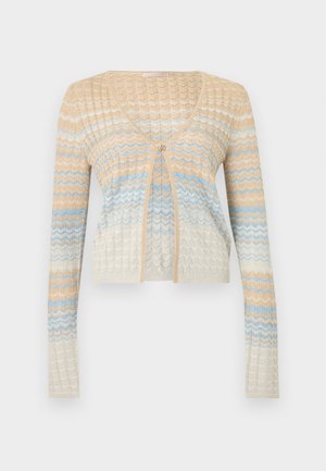 Smėlinės, baltos ir šviesiai mėlynos spalvų zigzago rašto megztinis su ilgomis rankovėmis, V formos iškirpte ir vienu sagos užsegimu priekyje centre.