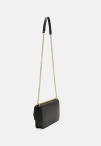 Borsa a tracolla nera in pelle con una tracolla in catena di metallo dorato e forma piatta e rettangolare. Presenta una superficie liscia e dettagli minimi.