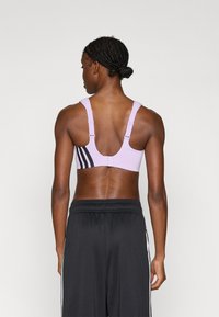 Αθλητικό μπουστάκι σε λιλά απόχρωση με ρυθμιζόμενους ιμάντες. Διαθέτει μαύρη λεπτομέρεια και σχέδιο racerback. Συνοδεύεται από μαύρο αθλητικό παντελόνι για αυξημένη άνεση.