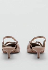 Sandalias de tacón de charol nude con punta redonda, tira en el tobillo y tacón de aguja de 5 cm, que exhiben un acabado suave y un detalle mínimo.