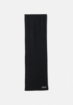 Black ribbed knit scarf with small rectangular Calvin Klein logo tag near one end on white background.