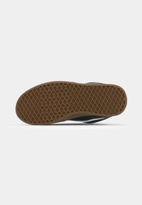 Fekete sneaker talp texturált gumi alsó résszel. Geometrikus mintázattal rendelkezik a tapadás érdekében, és lekerekített szélei a rugalmasságért.