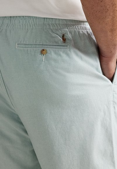 Lys blå bomullsshorts med elastisk midje, sidelommer, en baklomme med knapp og en liten brodert logo.