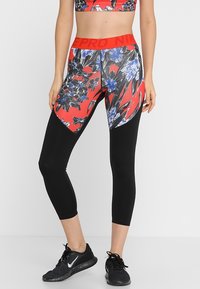 Leggings a fantasia floreale in rosso, blu e nero con una vita nera che presenta il marchio "PRO". Realizzati in materiale elasticizzato e traspirante.