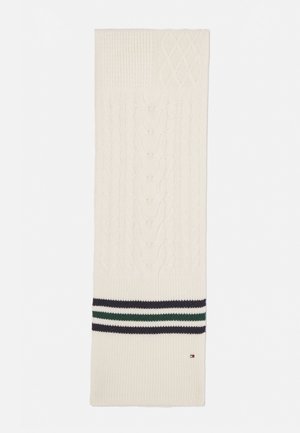 Kabelgebreide sjaal in roomkleur met textuurpatronen; heeft een horizontale band met marineblauwe, groene en witte strepen aan de onderkant.