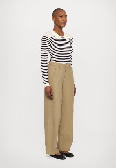 Camicia a maniche lunghe a righe in crema e blu navy, con colletto. Pantaloni larghi beige con linee pulite e una finitura testurizzata. Ballerine nere.
