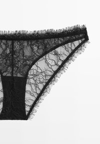Black lace panties featuring floral patterns, sheer material, and a soft, frayed edge along the waistband and leg openings.