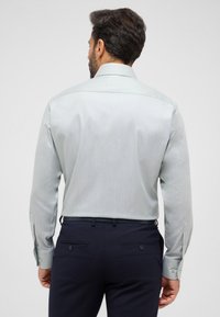Lichtgroen gestreept overhemd met een button-down kraag, lange mouwen en een textuurstof, gedragen met donkere broeken.