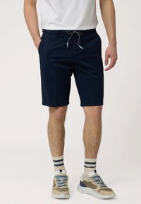 Marineblauwe shorts met een koord in de taille, zijzakken en een rechte voorkant. Gemaakt met gestreepte sokken en veelkleurige sneakers.