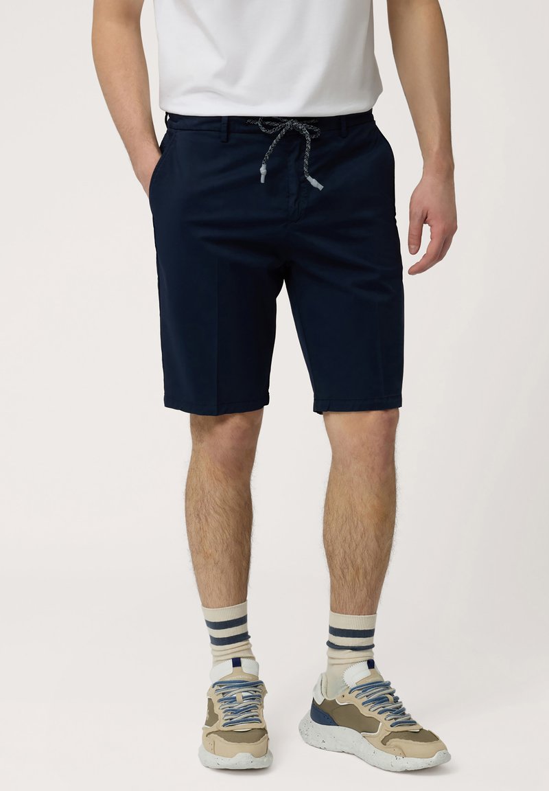 Marineblauwe shorts met een koord in de taille, zijzakken en een rechte voorkant. Gemaakt met gestreepte sokken en veelkleurige sneakers.