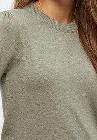 Ljusgrå stickad tröja med rund halsringning, som har subtil texts och lätt puffade ärmar.